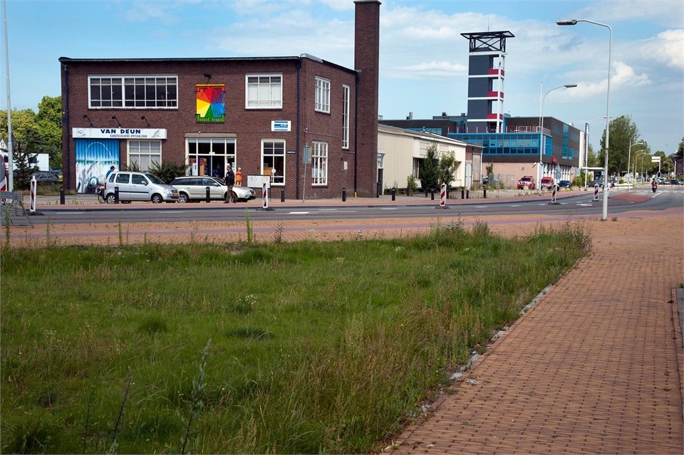 Doetinchem Iseldoks: foto met op de voorgrond gras en op de achtergrond fabriekspanden.