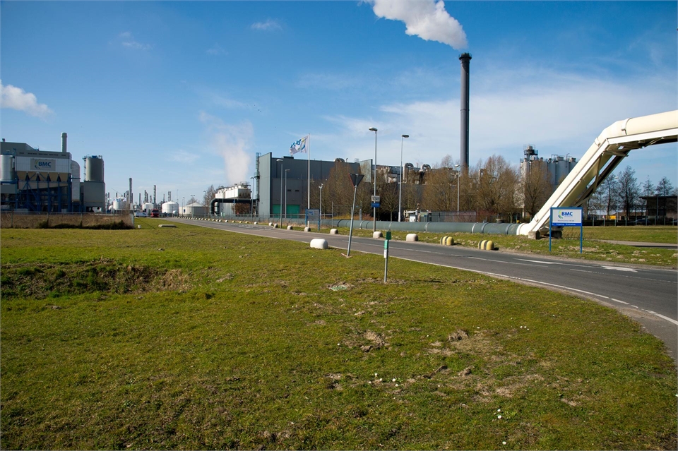 Noord-Brabant - Havengebied Moerdijk: foto met op de voorgrond gras en op de achtergrond een pijp waar rook uit komt en een buisleiding.